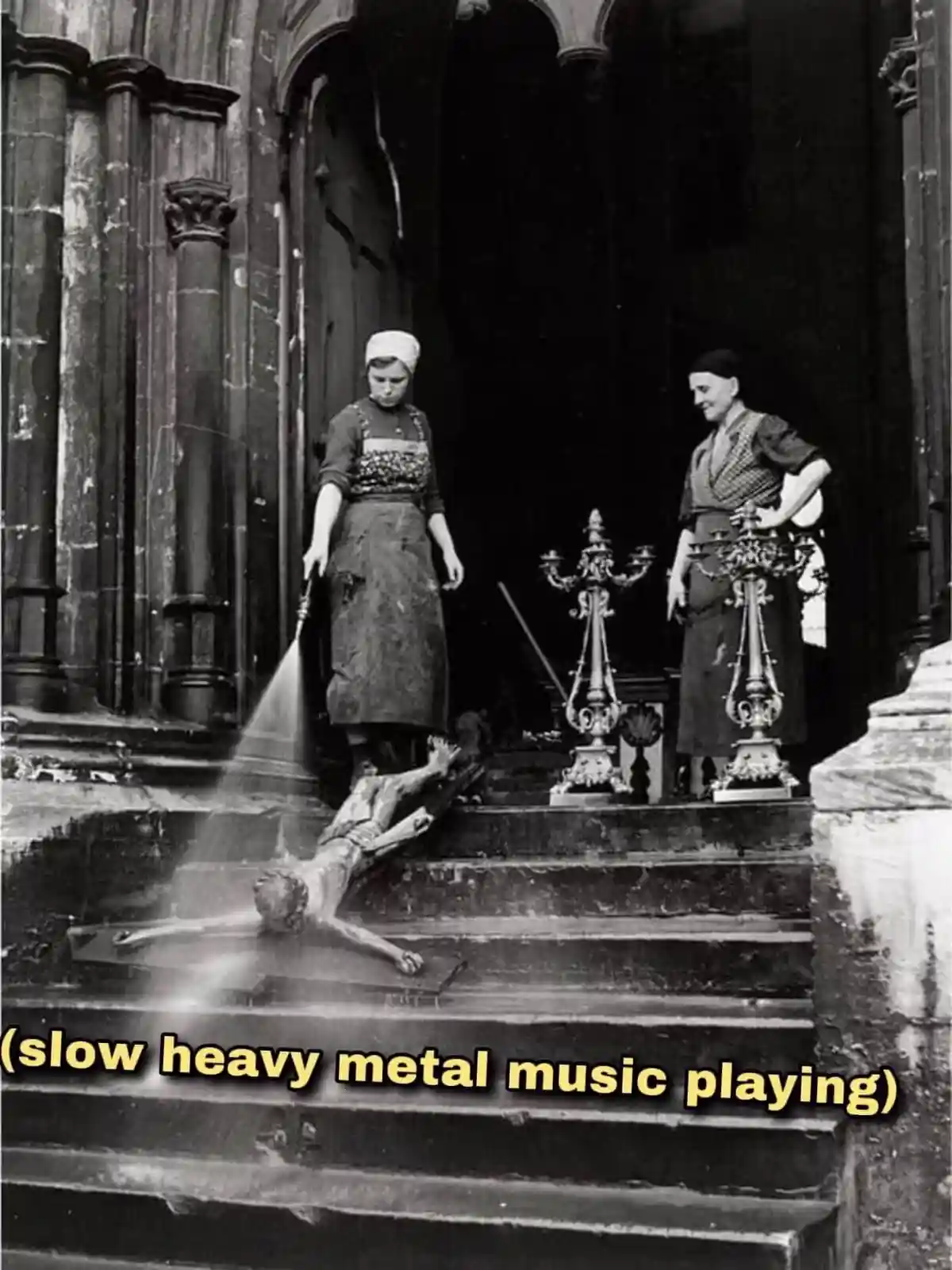 A black-and-white historical photo shows two women in aprons standing on stone steps outside a church. One woman is spraying…