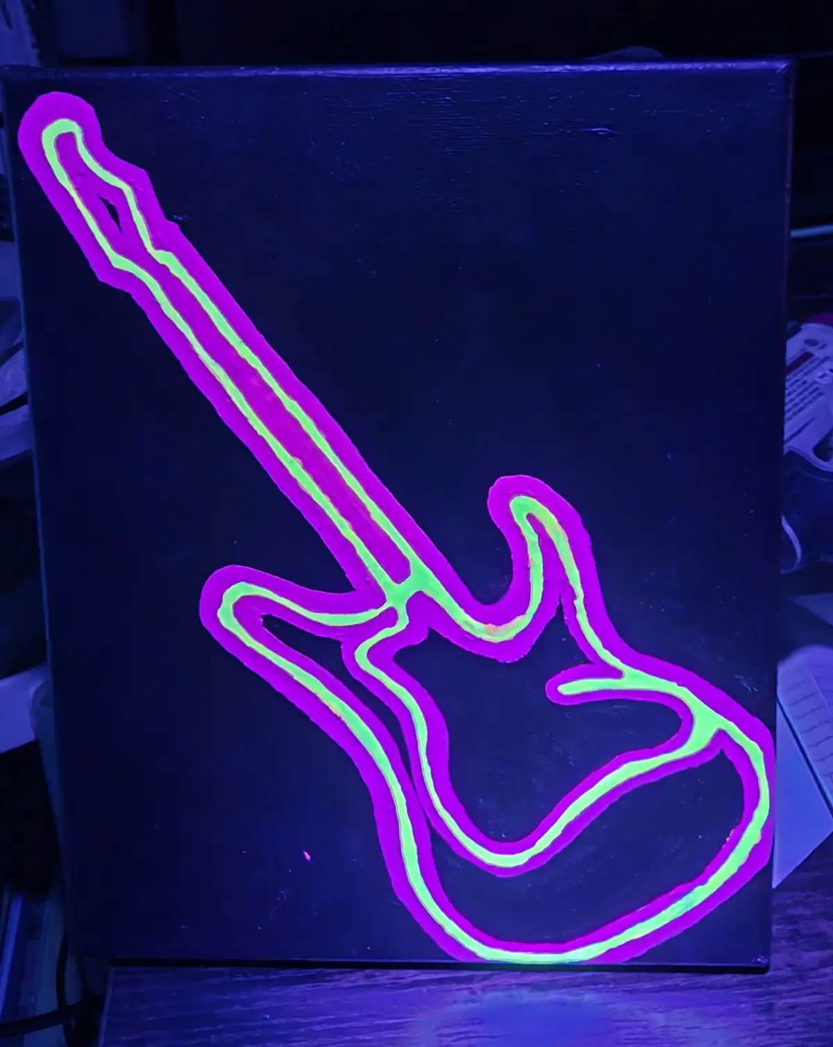 A black canvas displays a glowing outline of an electric guitar painted in neon purple and green, illuminated under…