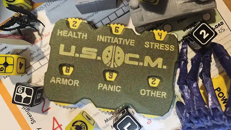 A close-up photo shows a green, 3D-printed character sheet labeled 'U.S.O.C.E.M.' with stats like Health 2, Initiative 6…