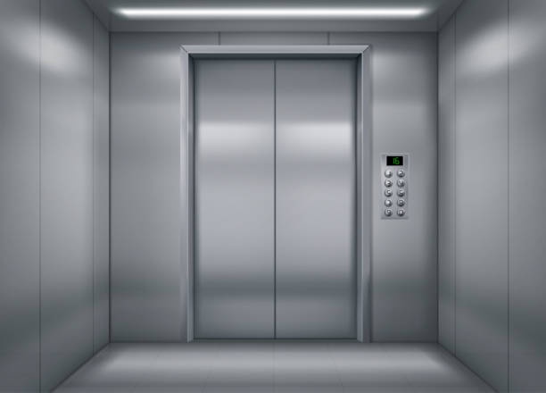 An empty, modern elevator with stainless steel walls and doors, featuring a digital display showing '16' and a keypad on the…