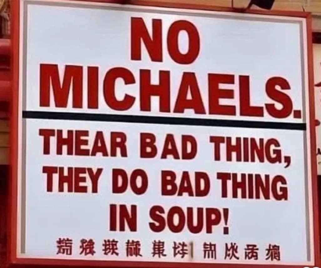 A white sign with red text reads 'NO MICHAELS. THEAR BAD THING, THEY DO BAD THING IN SOUP!' with a line of Chinese…