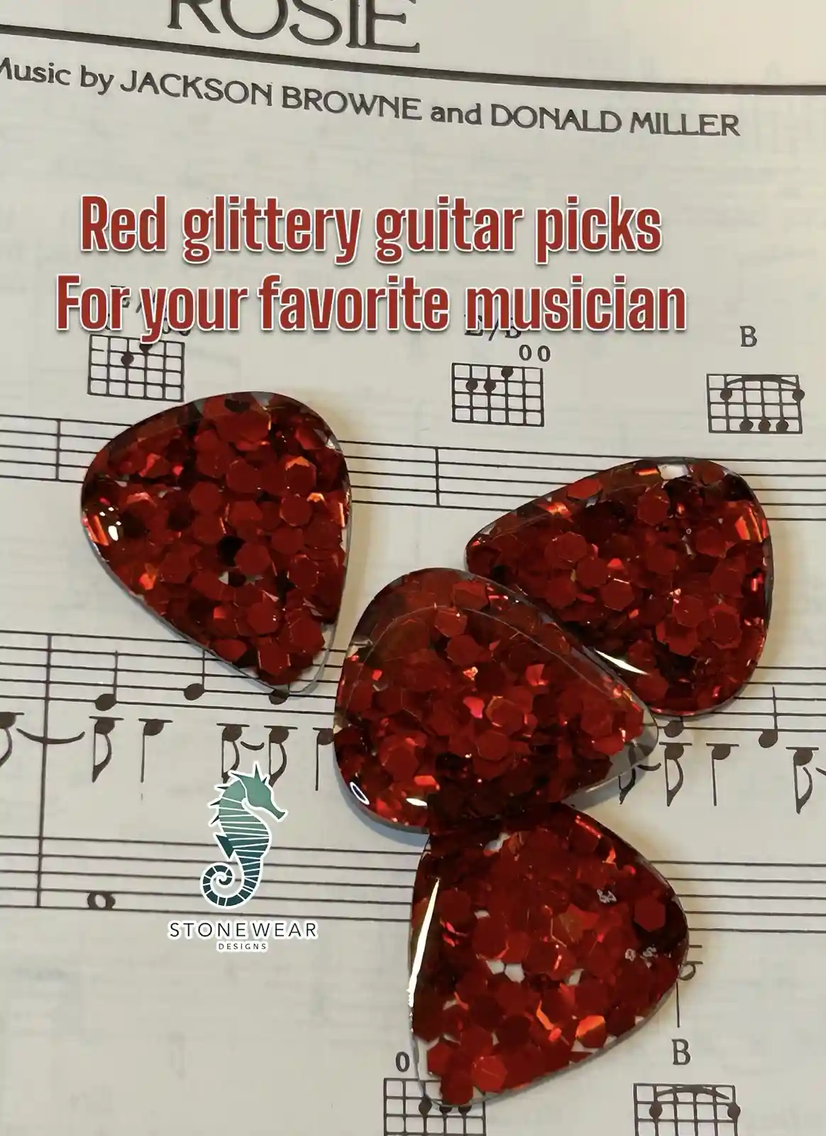 Four red glittery guitar picks are arranged in a butterfly shape on a sheet of music titled 'Rosie' by Jackson Browne and…
