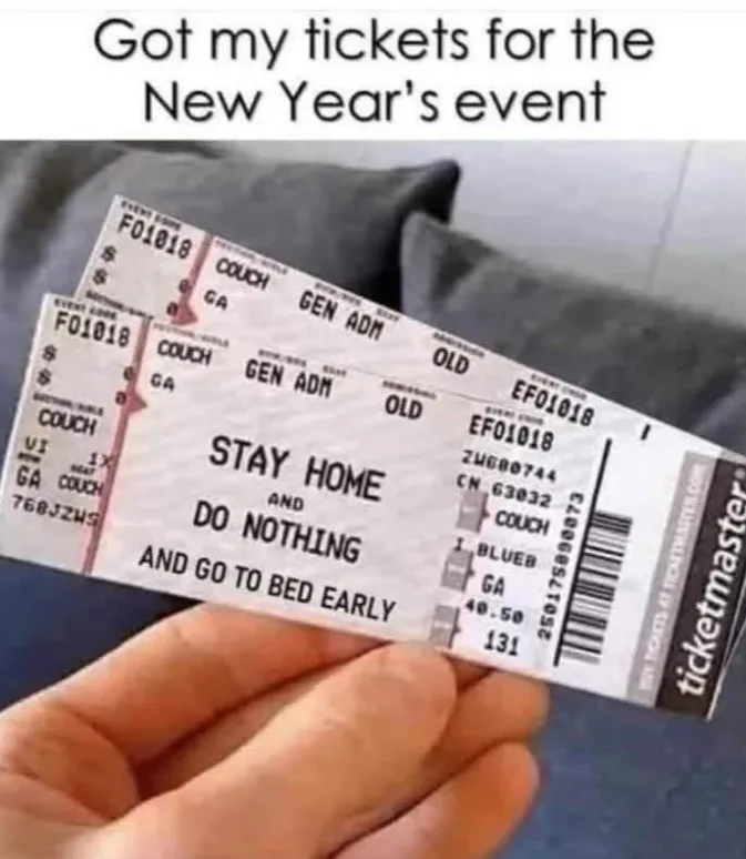 A hand holds two mock concert tickets from Ticketmaster, printed with 'STAY HOME AND DO NOTHING AND GO TO BED EARLY' as the…