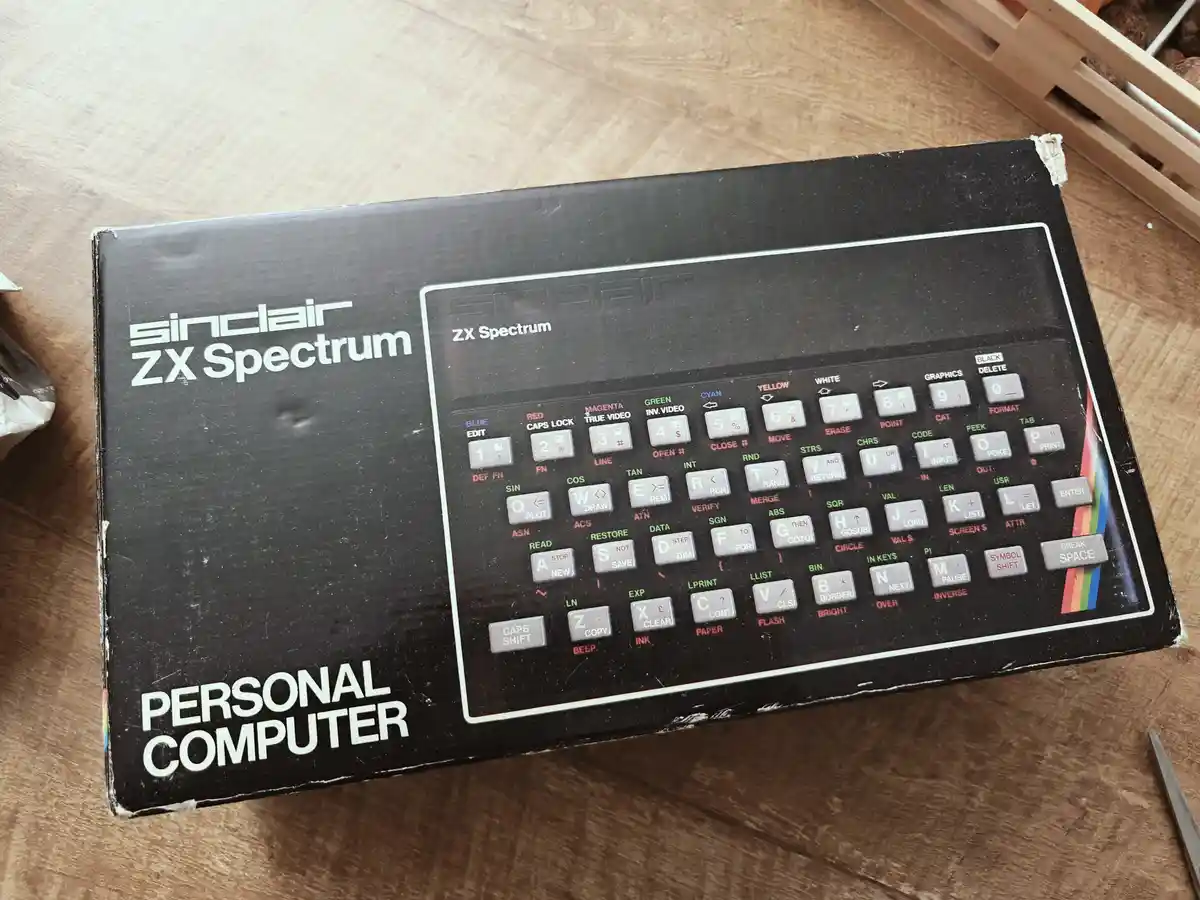 A close-up of a vintage Sinclair ZX Spectrum personal computer box, showing its iconic black packaging with a large graphic…