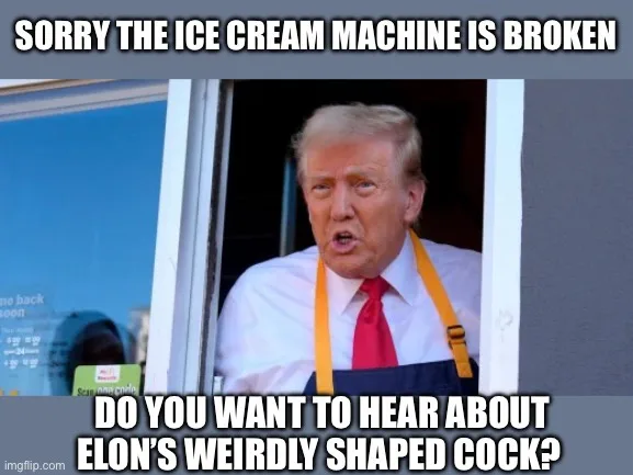 A man with blond hair wearing a white shirt, red tie, and blue apron with orange straps peers out from a service window. The…