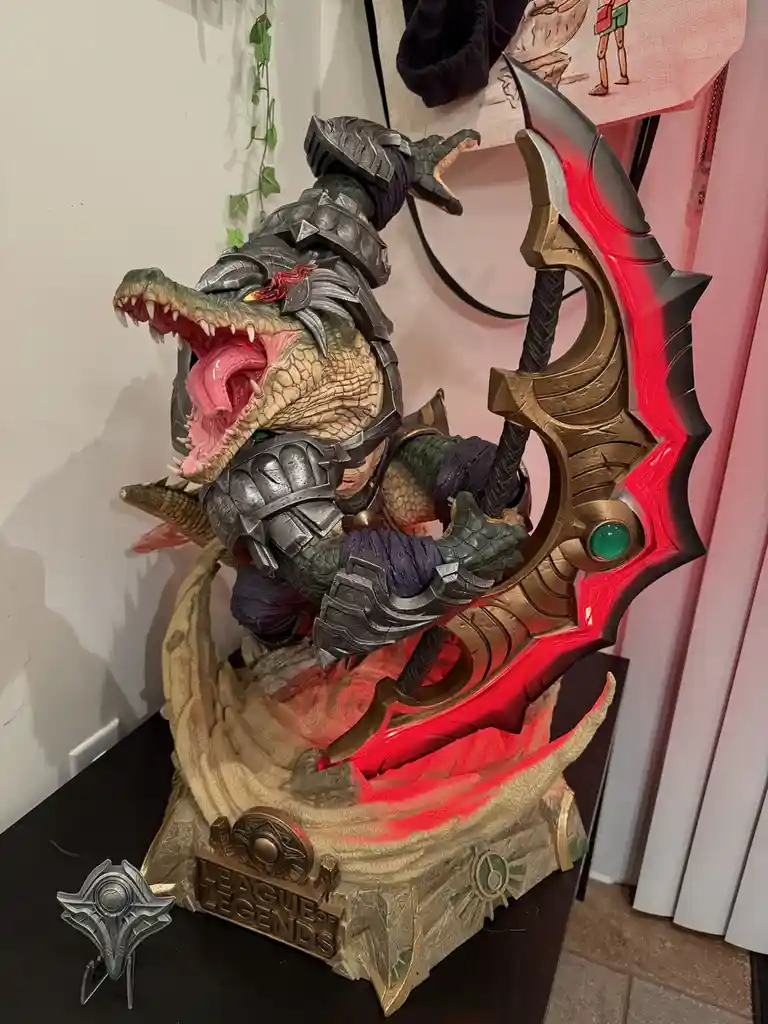 A detailed, illuminated statue of the League of Legends character Draven, a crocodile-like warrior in armor, roaring while…