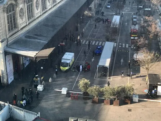 an aerial view of a street scene with emergency vehicles including an ambulance and fire truck, police officers, and people…