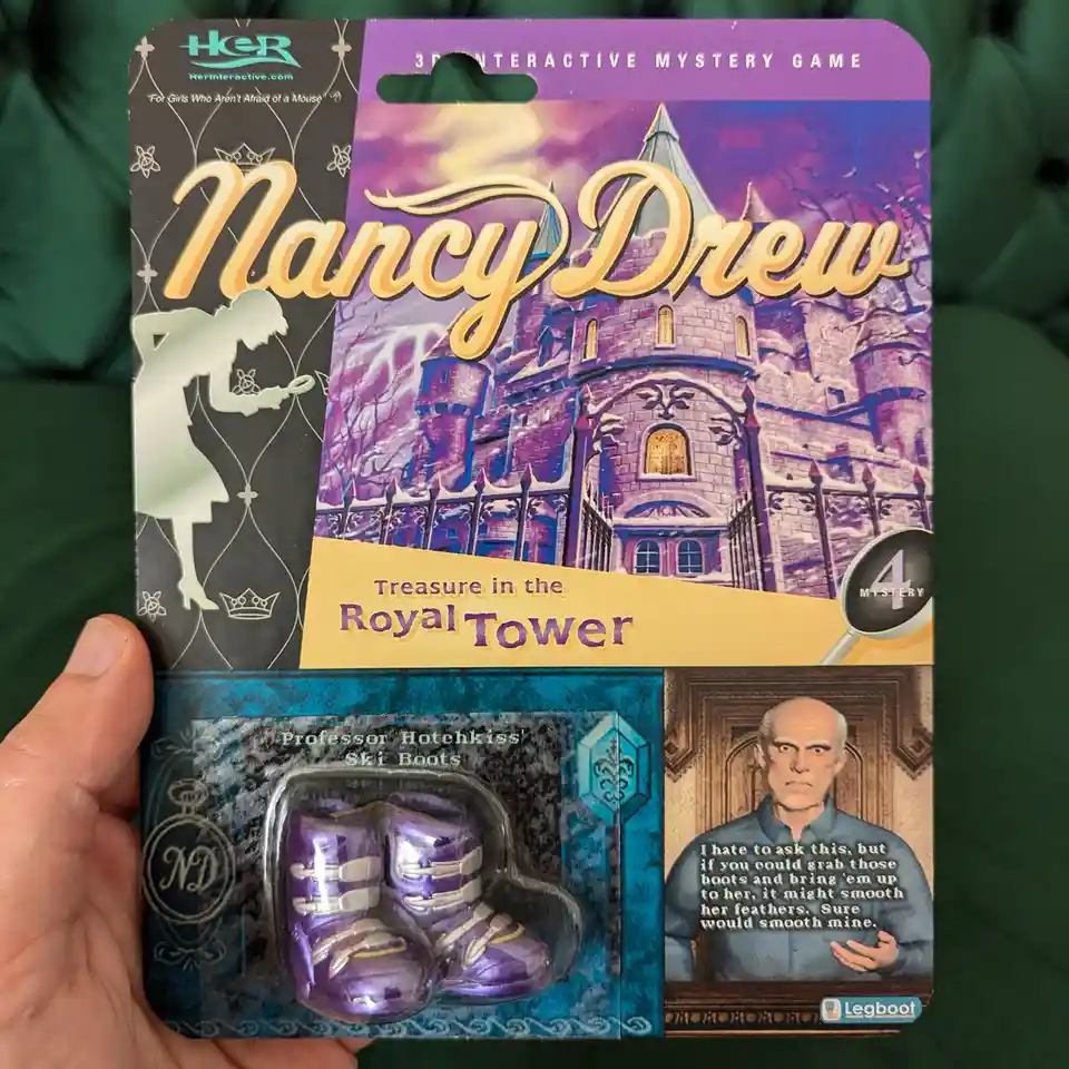 A hand holds a 'Nancy Drew: Treasure in the Royal Tower' 3D interactive mystery game package. The lower section displays a…