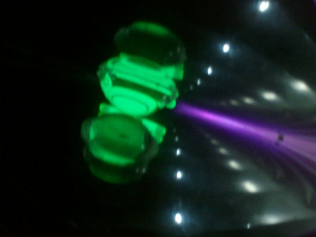 A blurry, low-resolution photo shows a glowing green object, possibly a decorative light or part of a ride, in a dark…