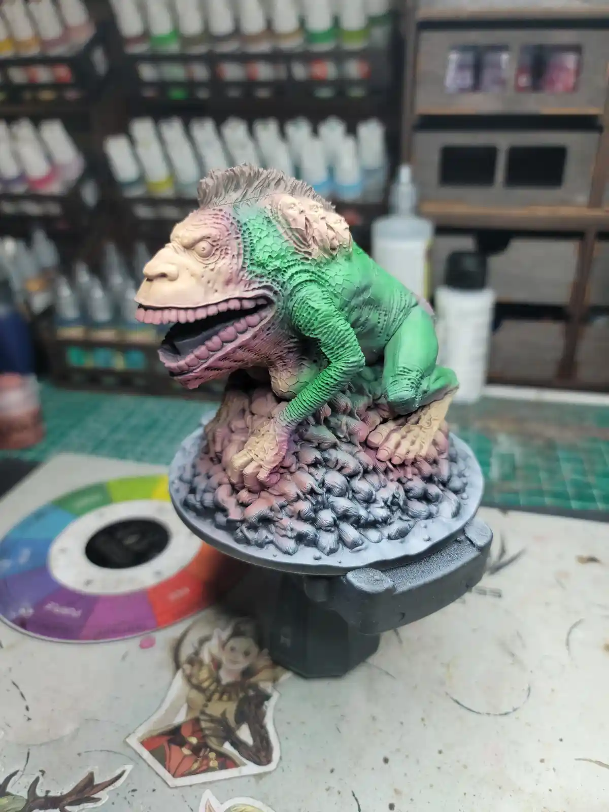 A detailed miniature figurine of a grotesque, green-skinned, multi-headed monster with a monkey-like face, painted and posed…