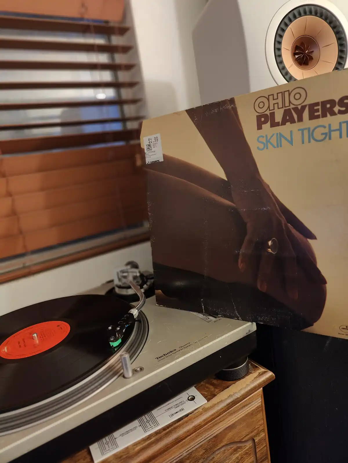 A close-up photo shows a vintage Technics turntable with a vinyl record spinning, next to the album cover for 'Skin Tight'…