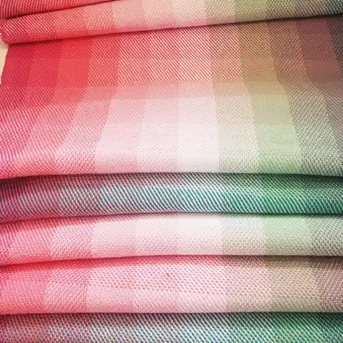 A close-up of neatly folded fabric swatches in various pink, green, and teal hues with visible woven textures. The overlaid…