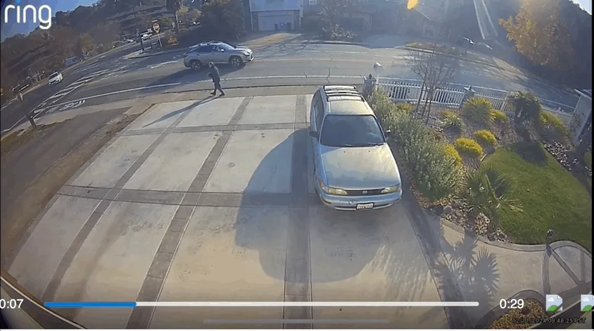 A six-panel security camera sequence from a Ring doorbell, showing a person walking toward a driveway with a parked silver…