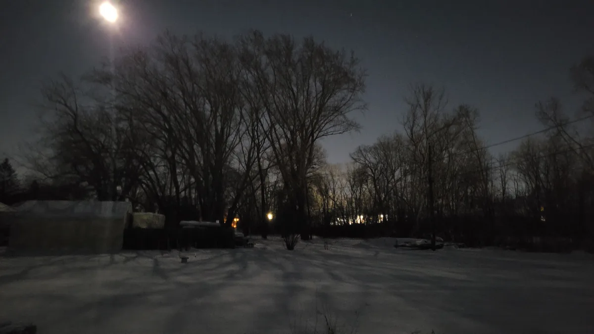 A snowy, nighttime outdoor scene with bare trees, a bright streetlamp, and distant lights, overlaid with the text 'i'm not a…