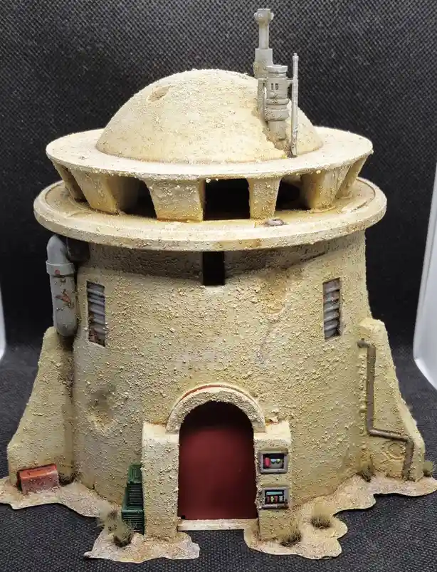 a detailed miniature model of a star wars jedi temple, featuring a sandy beige dome, arched red door, small windows, and…