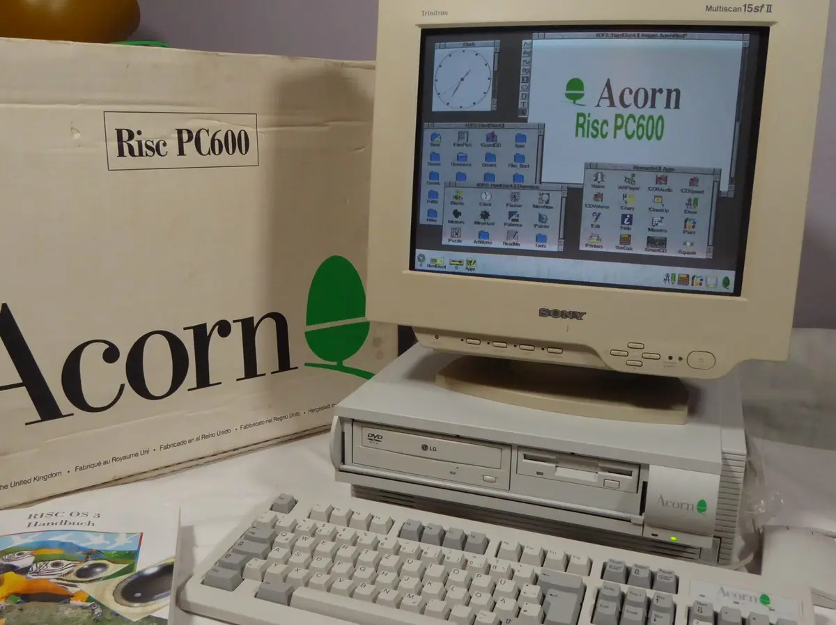 An Acorn Risc PC600 computer with a Sony Trinitron monitor displays its RISC OS 3 desktop, featuring a clock widget and…