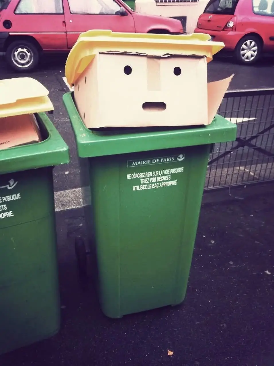 A green public trash bin in Paris, labeled 'MAIRIE DE PARIS' and with French text instructing citizens to not leave items on…