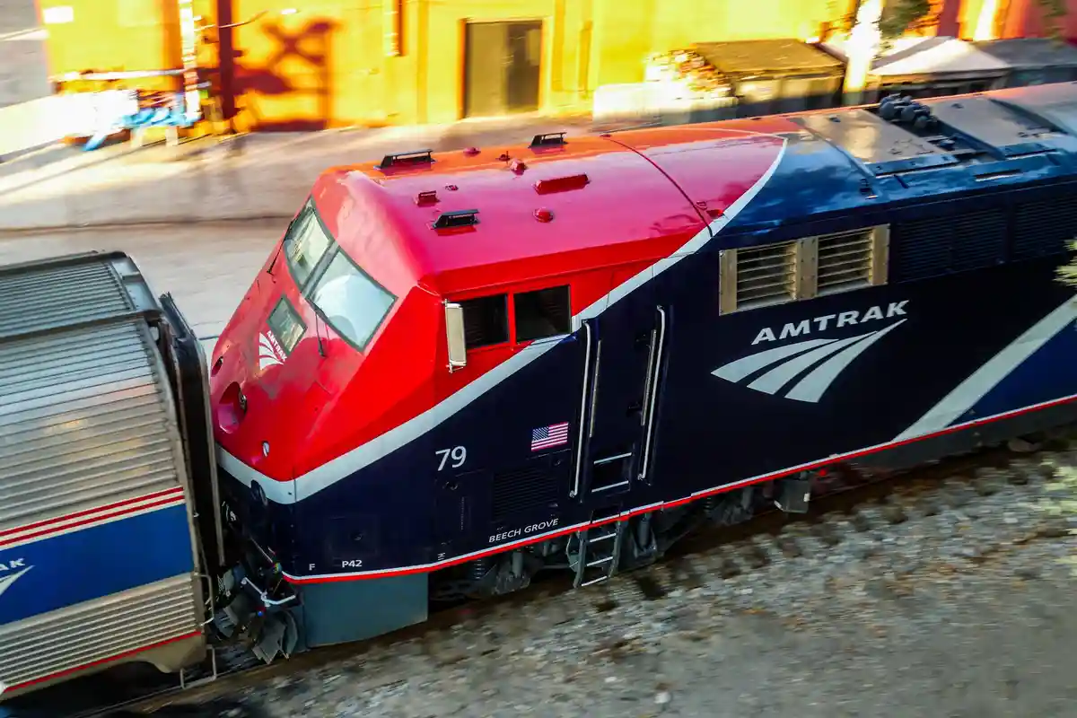 A red, white, and blue Amtrak locomotive, numbered 79 and named 'Beech Grove', is captured in motion with a blurred…