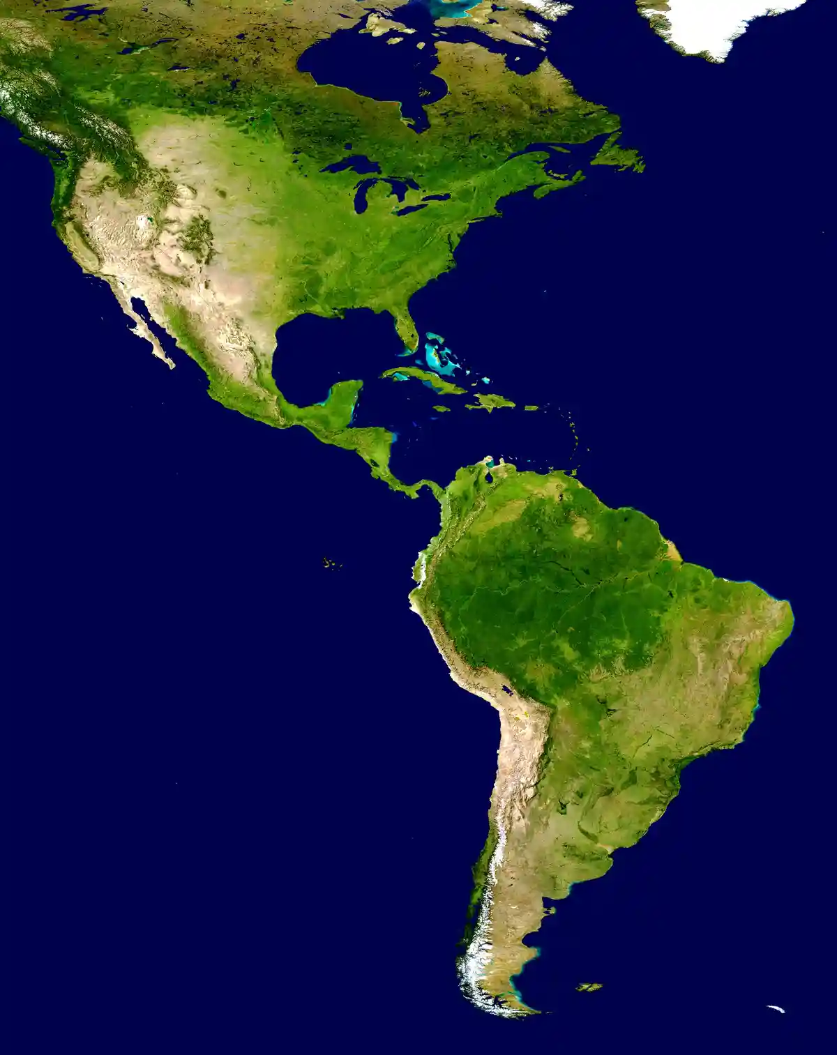 A satellite image shows the continents of North and South America from space, with green landmasses and dark blue oceans…