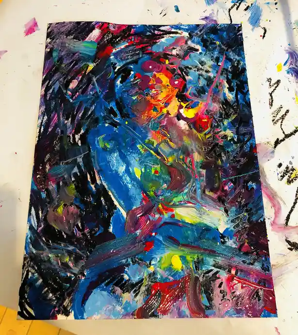 A vibrant, abstract painting with chaotic brushstrokes of blue, red, yellow, and black sits on a paint-splattered white…