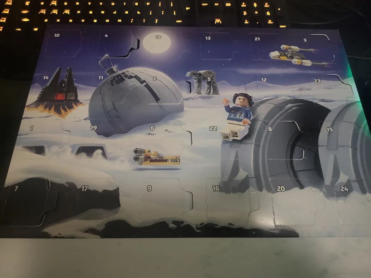 A photo of a LEGO Star Wars Advent calendar with numbered flaps, set against a snowy Hoth landscape with characters and…