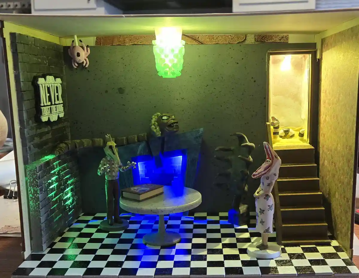A miniature diorama of a creepy, dimly lit room with a black-and-white checkered floor, featuring grotesque figurines…