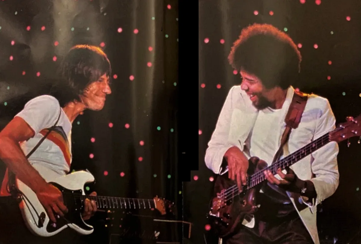 The image shows two side-by-side photos of musicians on stage, both smiling and playing electric guitars against a backdrop…