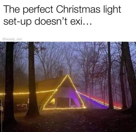A cabin in a foggy forest at dusk is outlined with bright yellow string lights forming a triangle on its roof and walls. A…