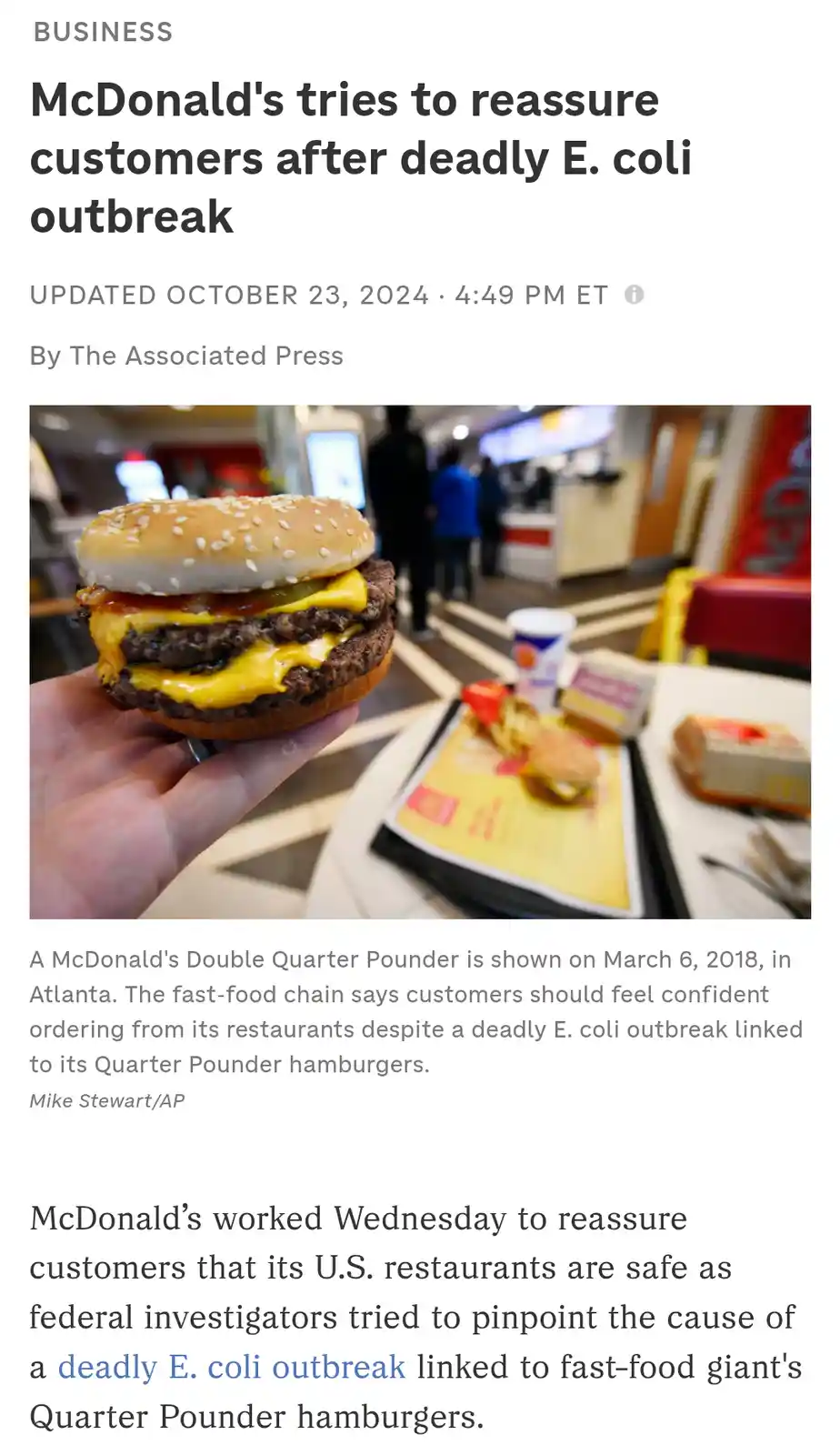 A news article screenshot shows a hand holding a McDonald's Double Quarter Pounder burger, with other McDonald's food items…