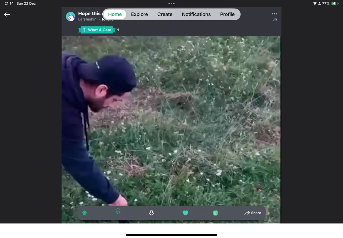 A screenshot of a social media post shows a person in a dark hoodie and cap bending over in a grassy field, seemingly…