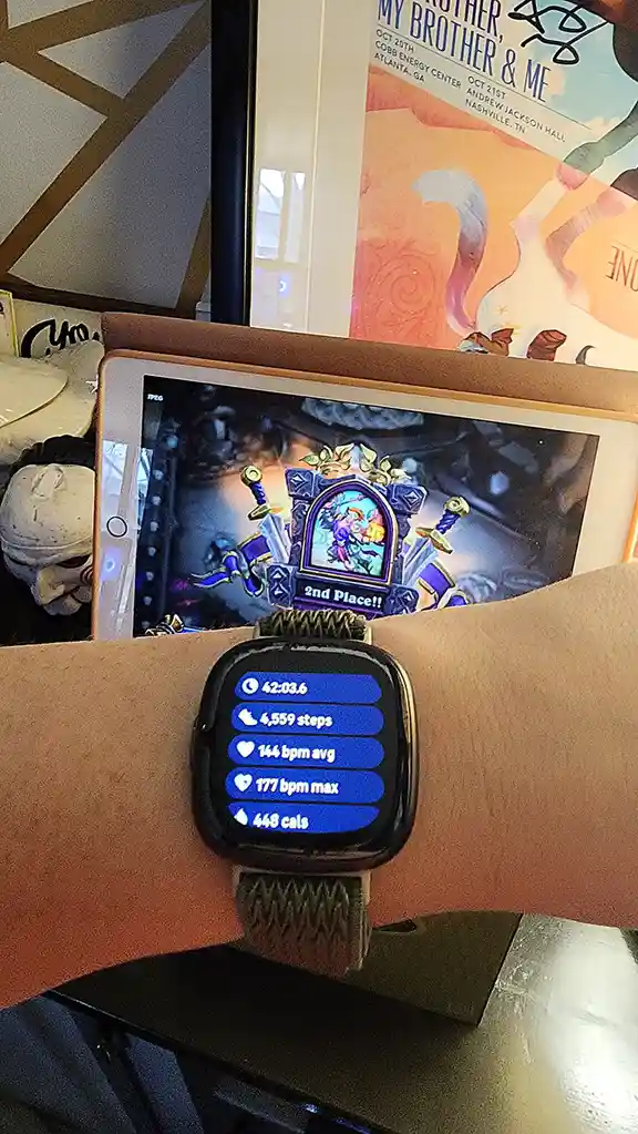 A close-up photo shows a smartwatch on a person's wrist displaying fitness stats: 42:03.6 time, 4,559 steps, 144 bpm avg…