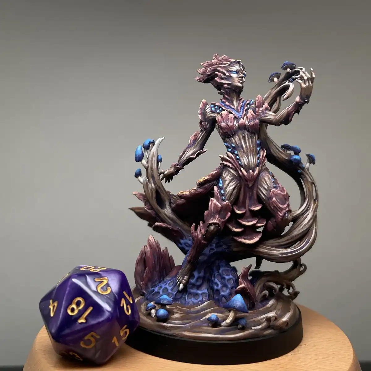 A highly detailed fantasy figurine of a mushroom-themed humanoid creature with flowing, vine-like limbs and blue mushrooms…