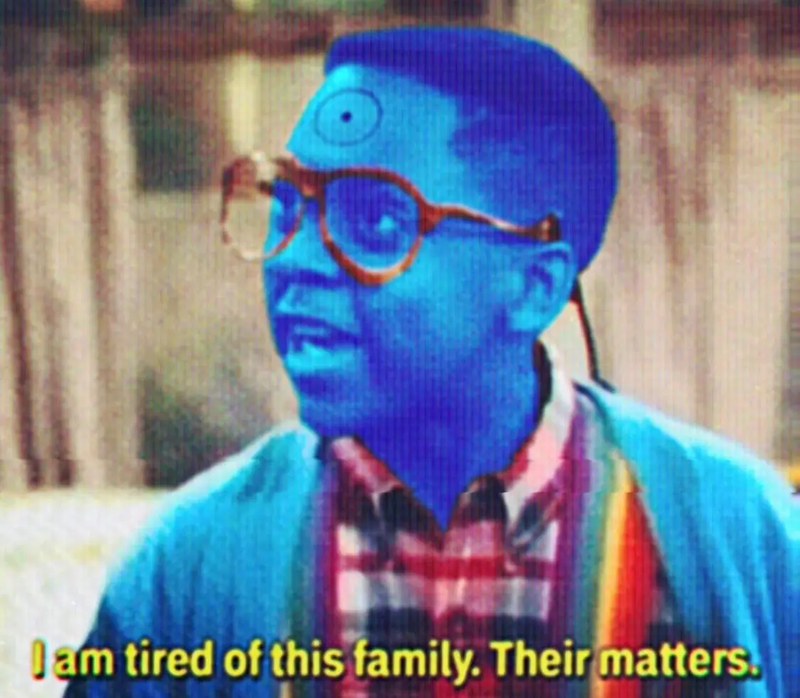 A blue-tinted image of a man with glasses and a rainbow scarf, his face edited to have an extra eye on his forehead, with…