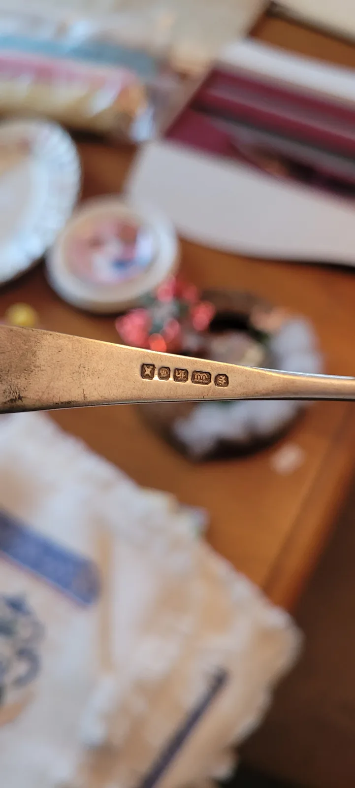 A close-up photo shows the hallmark stamps on the handle of a silver utensil, which include the marks 'x', '4', 'm', and…