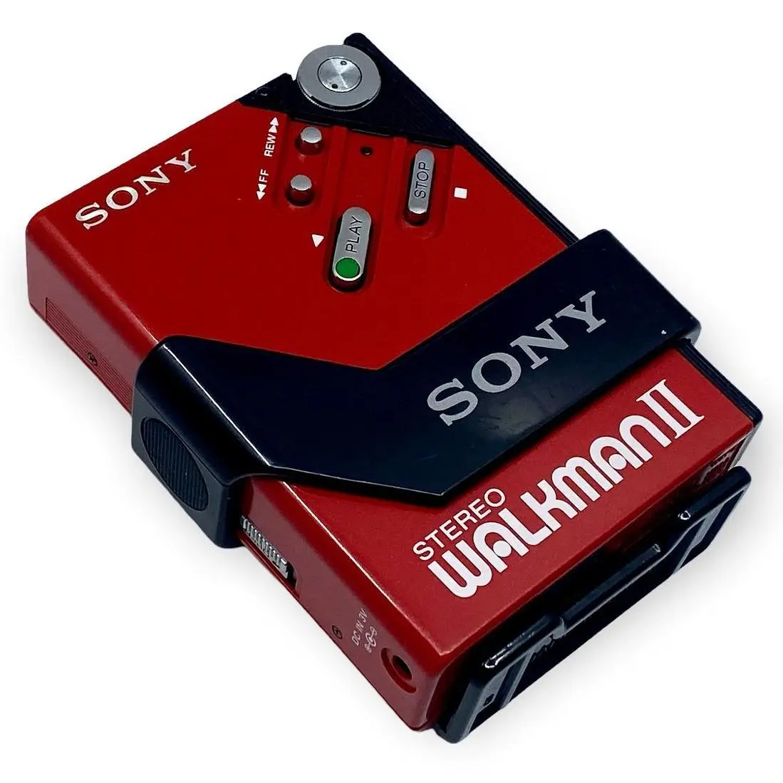 A red and black Sony Walkman II portable cassette player is shown with its own casing partially peeled back to reveal the…