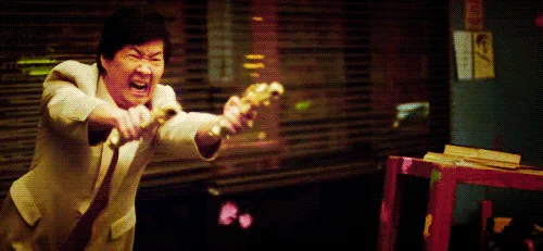 A split-screen image shows a man in a beige suit aiming a water gun with an intense expression, followed by a woman in a…