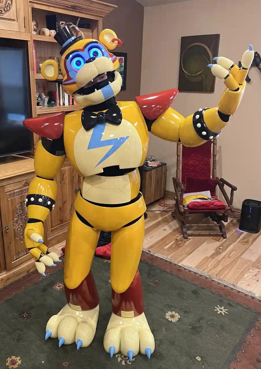 A large, yellow animatronic bear with glowing blue eyes, a black bowtie, and a lightning bolt on its chest stands in a…