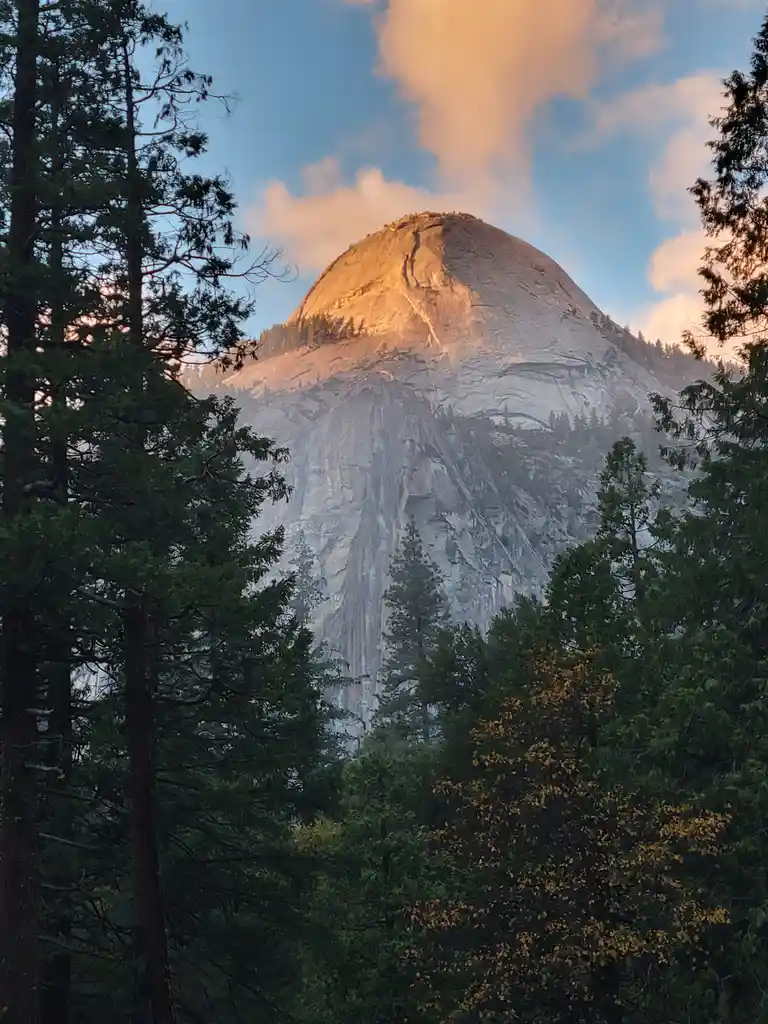 A scenic photograph shows the iconic Half Dome mountain in Yosemite National Park, its granite face bathed in golden…