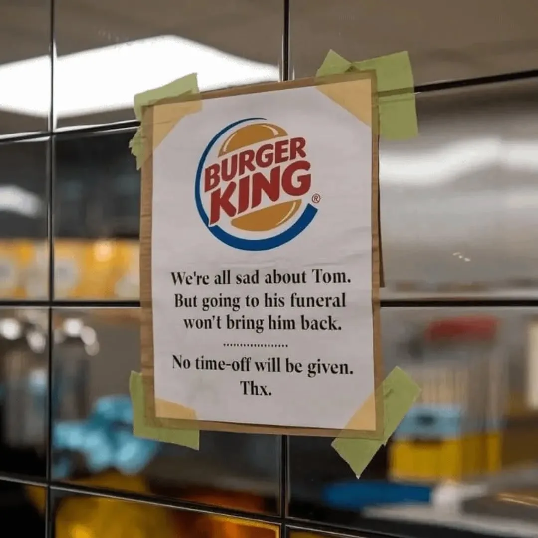 A printed notice with the Burger King logo is taped to a glass door, announcing that employees are saddened by the death of…
