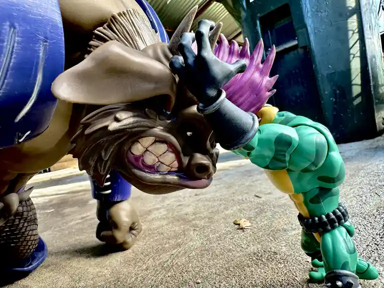 A close-up photo shows two action figures in a dramatic pose: a large brown bull-like monster with a purple mohawk and a…