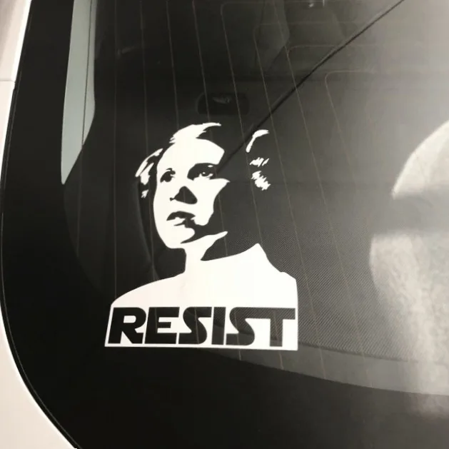 A black-and-white vinyl decal on a car window shows a stylized portrait of Princess Leia from Star Wars, looking determined…