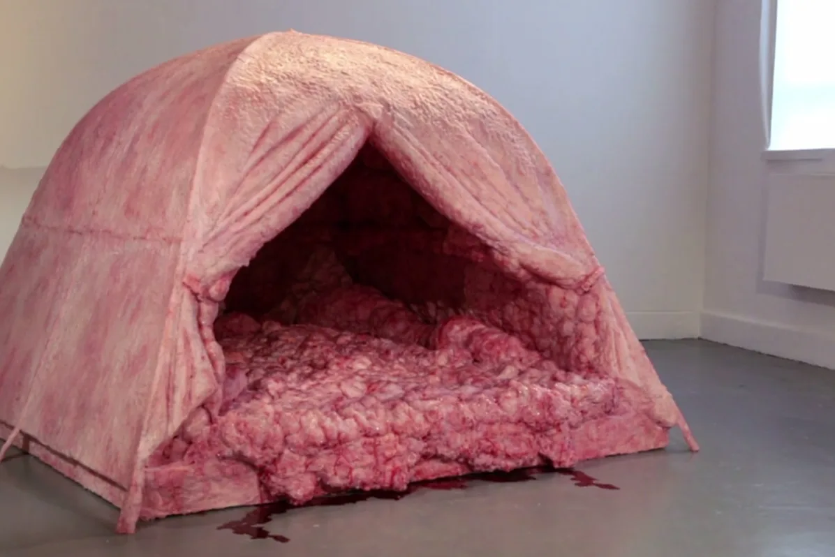 A large, dome-shaped tent made entirely of pink, textured meat with a gruesome, bloody appearance, set in a sterile white…