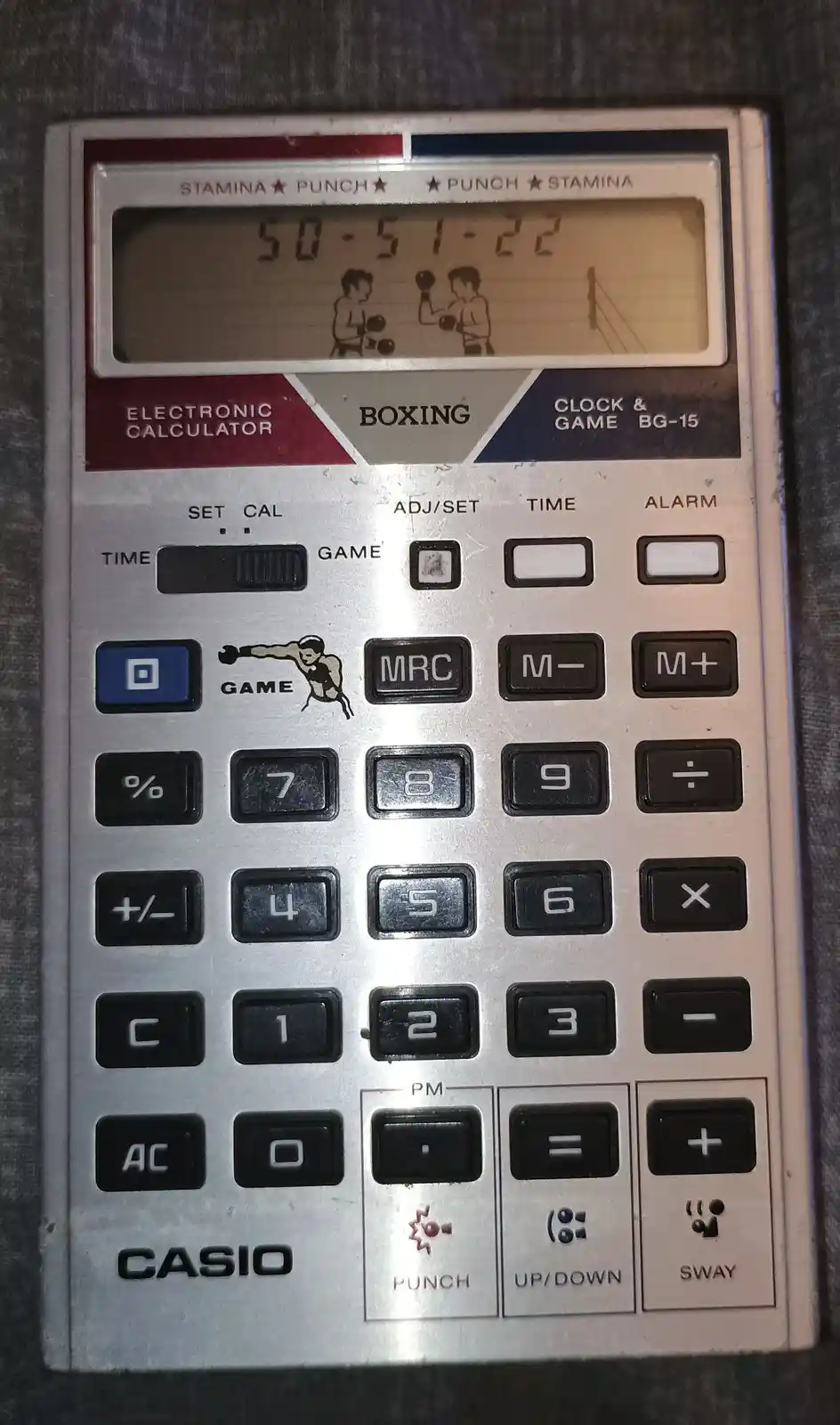 A vintage Casio BG-15 electronic calculator with a built-in boxing game, displaying the score '50-51-22' on its screen while…