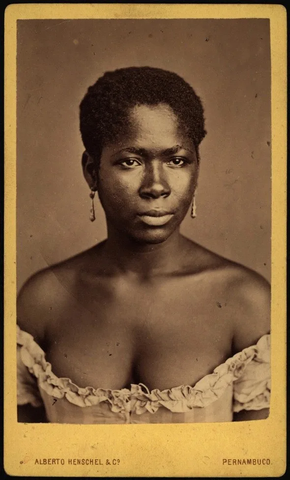 A vintage sepia-toned portrait of a Black woman with short hair and dangling earrings, wearing an off-the-shoulder ruffled…