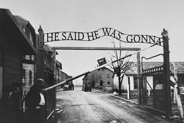 A black-and-white historical photo shows a barbed-wire gate with a sign reading 'HE SAID HE WAS GONNA' above it, blocking a…