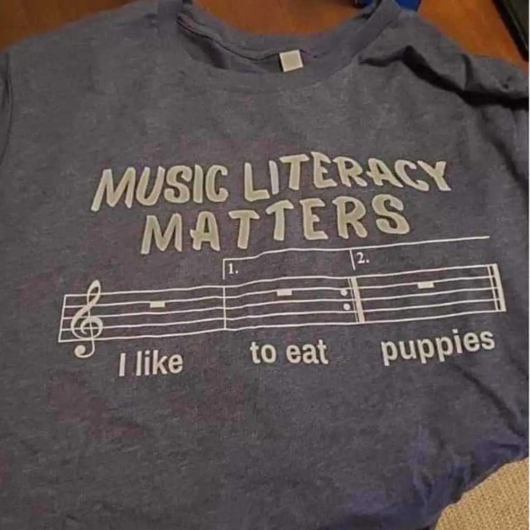 A gray t-shirt displays the phrase 'MUSIC LITERACY MATTERS' above a musical staff with two measures. The first measure is…