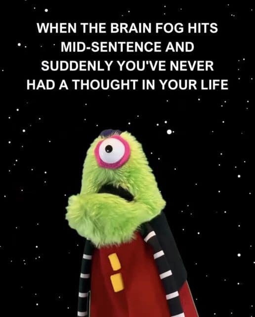 A green, one-eyed, furry monster puppet with a red cape and black-and-white striped sleeves stands against a starry black…